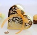 Detailed macro of golden laser-cut heart favor box with rose patterns and ribbon - Reflective Gold