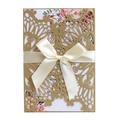 Close-up of laser-cut gold glitter wedding invitation with cream ribbon and floral card - Beige Gold