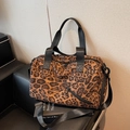 Borsa tote leopardata con manici neri e tracolla rimovibile su una poltrona in pelle - Stampa leopardata