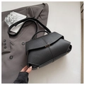 Close-up of black pebble leather shoulder bag with white contrast stitching and metal buckle - Black