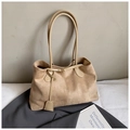 Detail of suede tote bag with leather strap and tassel on soft white background - Khaki
