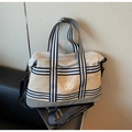 Close-up of a canvas travel bag with striped webbing and embroidered logo on a black chair - One Size / Gray