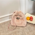 Pink plush bucket bag with golden buckle and leather strap in a lifestyle setting - Pink