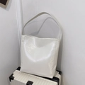 Detalle de un bolso tote minimalista blanco roto con cuero brillante sobre una maleta - Blanco