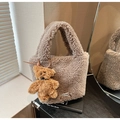 Close-up of brown plush bucket bag featuring a teddy bear charm and brand logo tag - Gray (With Bear Pendant)