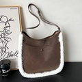 Brown suede underarm bag with white faux fur trim and adjustable strap in a cozy setting - Brown