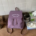 Dettaglio dello zaino in nylon viola con ricamo bianco e chiusura a coulisse su tavolo - Viola