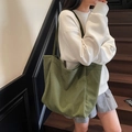 Olive green corduroy tote bag for women shown as a crossbody shoulder bag on a model - Green