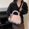 Bolso de peluche rosa con asa de cuero y amuleto de oso mostrado en una modelo - Rosa con colgante