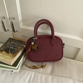 Sac bowling bordeaux vintage avec gland en cœur et bandoulière sur fond de tissu - Rouge avec Pendentif