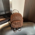 Mini sac à dos marron à motif léopard avec détails dorés sur un fauteuil en cuir - Léopard Café