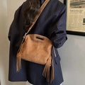Brown faux suede crossbody bag with side fringes and cutout handle shown on model - Brown