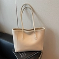 Chic beige lychee grain leather tote bag with slim shoulder straps on a book - Off White