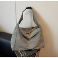 Detail view of green textured tote bag with adjustable black buckle strap on a book - Green
