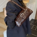 Close-up of retro dark brown leather underarm bag with silver rivets and metal buckle - Brown