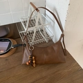 Dettaglio borsa a mezzaluna marrone con ciondolo in legno vintage e finiture della zip - Marrone