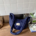 Dettaglio della borsa imbottita blu navy con ricamo a cuore e toppa con logo in perla - Blu