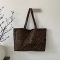 Dettaglio borsa tote leopardata in velluto a coste appesa a una parete con rami - Marrone