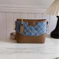Bolso hobo de mezclilla acolchada y cuero marrón con cadena dorada sobre mármol - Azul