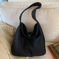 Grande borsa hobo leopardata nera con tracolla larga su un divano in tessuto bianco - Nero