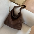 Borsa tote in pelle scamosciata leopardata marrone su un divano color crema - Marrone