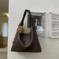 Detail der dunkelbraunen Hobo-Tasche mit Plüschbären-Anhänger und bunten Perlenakzenten - Kaffee mit Anhänger