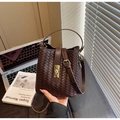 Detail der dunkelbraun gewebten Leder-Eimertasche mit goldener Schnalle im Lifestyle-Look - Kaffeebraun