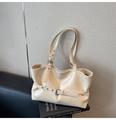 Détail du sac cabas en cuir crème avec boucles décoratives posé sur des livres - Blanc Cassé