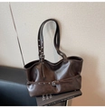 Détail d'un sac cabas vintage marron foncé avec boucles métalliques sur livres - Marron