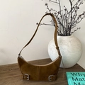 Braune Wildleder-Halbmondtasche mit silbernen Metallschnallen auf Holztisch - Braun