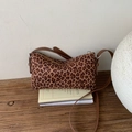 Detail der Vintage-Umhängetasche mit Leopardenmuster auf Holz mit braunem Lederriemen - Leopardenmuster