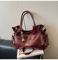 Detalle de bolso tote de cuero burdeos con cordón y colgante de estrella sobre un libro - Con Colgante / Rojo