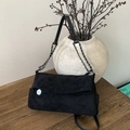Détail d'un sac bandoulière en daim noir avec matelassage en losange et chaîne argentée - Noir