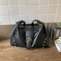 Black vintage studded tote bag in leather with silver buckle and rivets on wooden desk - Black