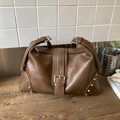 Brown vintage faux leather tote bag with silver studs and buckle on rustic wood surface - Brown