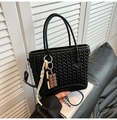 Detail of black quilted woven texture bucket bag with chocolate charm and crossbody strap - Black