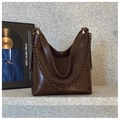 Detailed macro view of dark brown polished leather bucket bag with bronze chain strap - Brown
