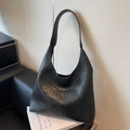 Große schwarze geflochtene Leder-Hobo-Tasche mit breitem Schultergurt auf Designbuch - Schwarz