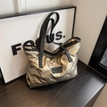 Sac fourre-tout matelassé doré métallique avec anses noires sur surface en bois - Or