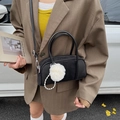 Black bowling bag with plush pompom and pearl charms carried by a model in suit - Black With Pendant