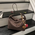 Dark brown suede dumpling shoulder bag with plush ball charm on a vintage staircase - With Charm / Brown