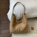 Detailansicht der braunen Wildlederstruktur einer Hobo-Tasche mit silbernen Metallösen - Khaki