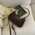 Detail einer dunkelbraunen Wildleder-Halbmondtasche auf einem gemütlichen cremefarbenen Sofa - Braun