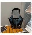 Detail of black faux leather tote with silver rivets and metal eyelets on a wood stool - Black
