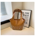 Detailed close-up view of brown riveted bucket bag with silver metal eyelets and studs. - Brown