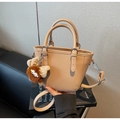 Detail of beige lychee pattern leather mini tote with a cute plush monster charm - Apricot