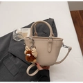 Detail of apricot pebbled leather handbag with cute brown plush monster charm and strap - Off-white