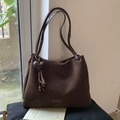 Detail van donkerbruine matte shopper met hartvormige hanger en franjes op een kussen - Met Hanger / Koffie met Hanger
