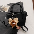 Black litchi grain tote bag with fuzzy monster charm and beige bow, crossbody style - Black