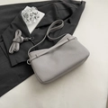 Bolso de hombro plisado gris claro con correa ajustable sobre fondo de traje elegante - Gris